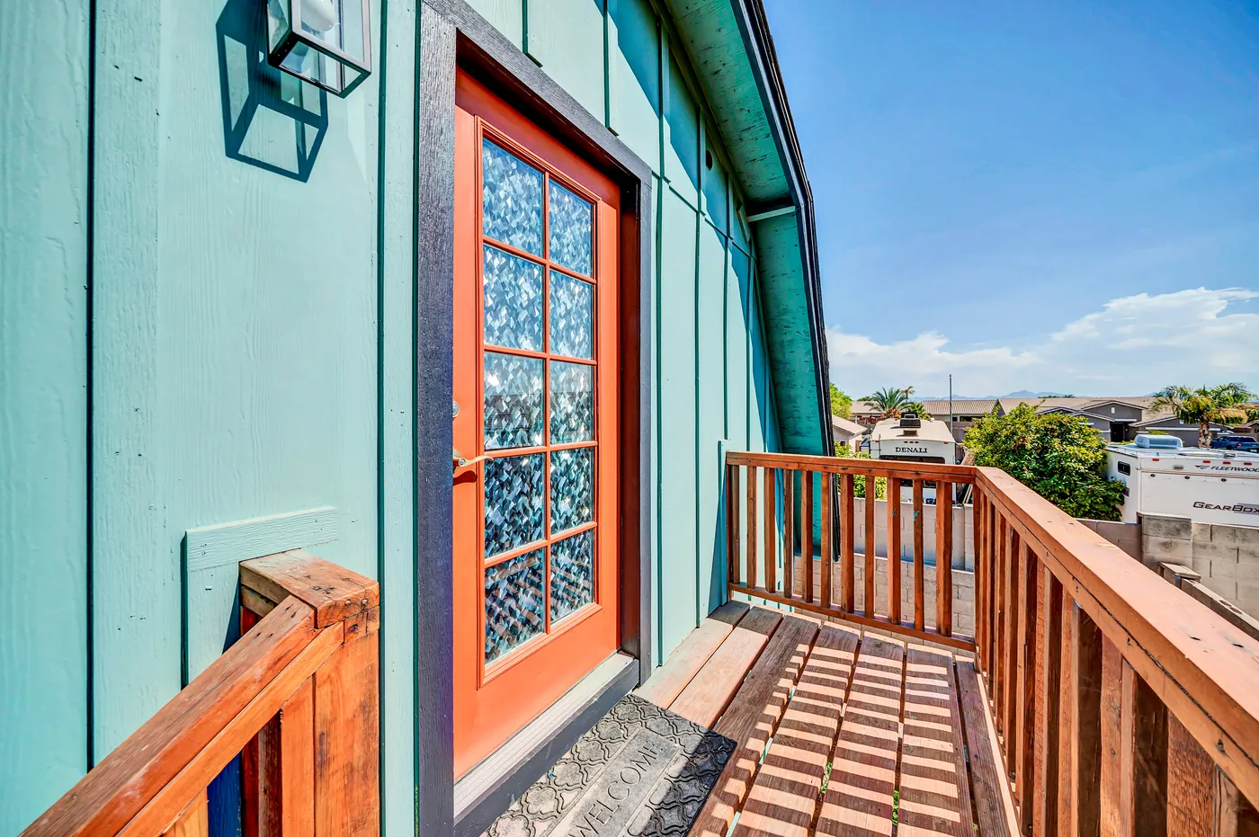 An orange door opening from the barn onto its upstairs deck and the sky.